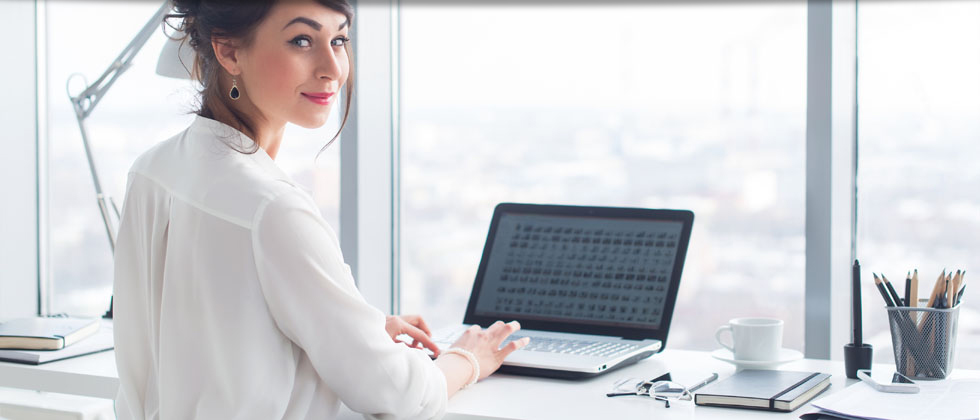 Smiling businesswoman on laptop in office
